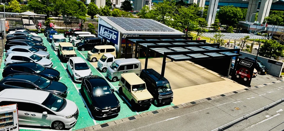 日中のN-style京都。敷地全体と黒いカーポート、道路から店舗前への入口
